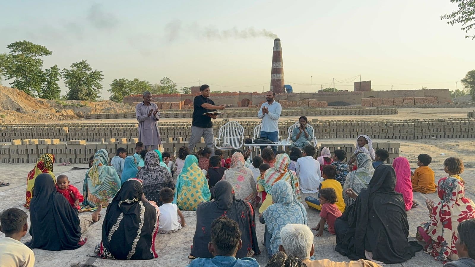 Families gathered at a brick kiln site for community outreach